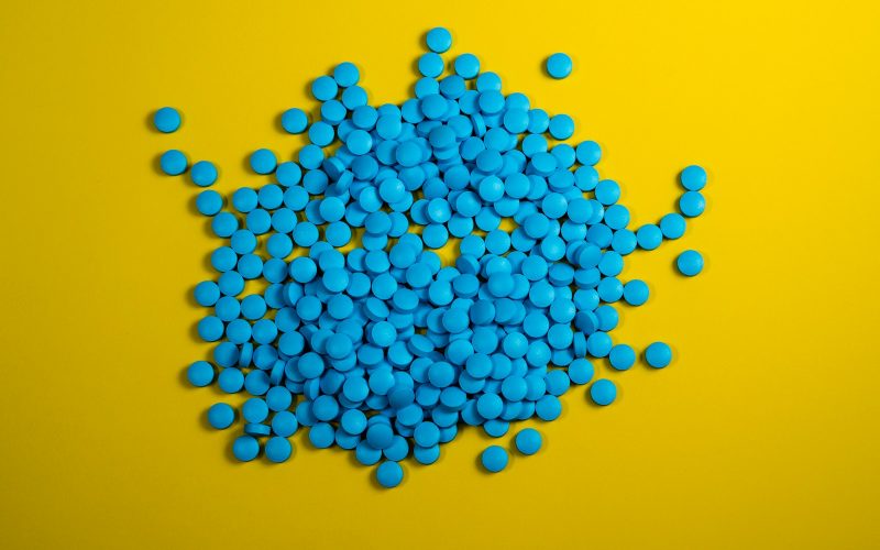 a pile of blue pills on a yellow background